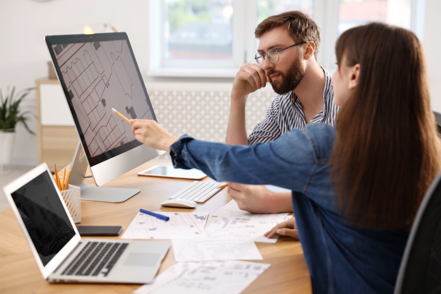 Two people discussing plans at desk