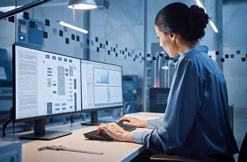 Woman working at dual computer screens